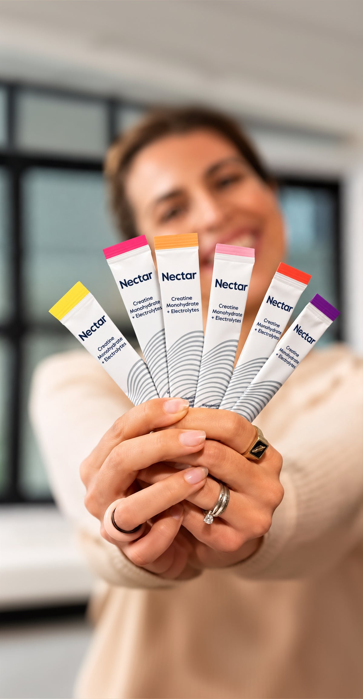 Smiling woman holding out a fan of Nectar stick packs